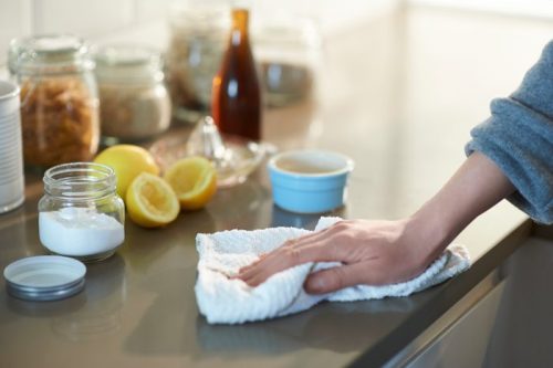 Woman cleaning a kitchen worktop with natural cleaning products lemon, bicarbonate of soda and vinegar.