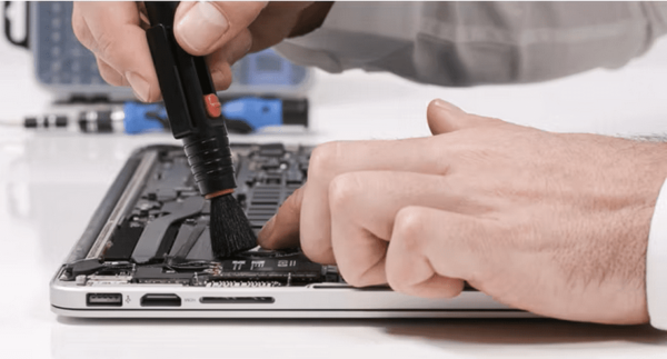 Person brushing dust out of a laptops ports
